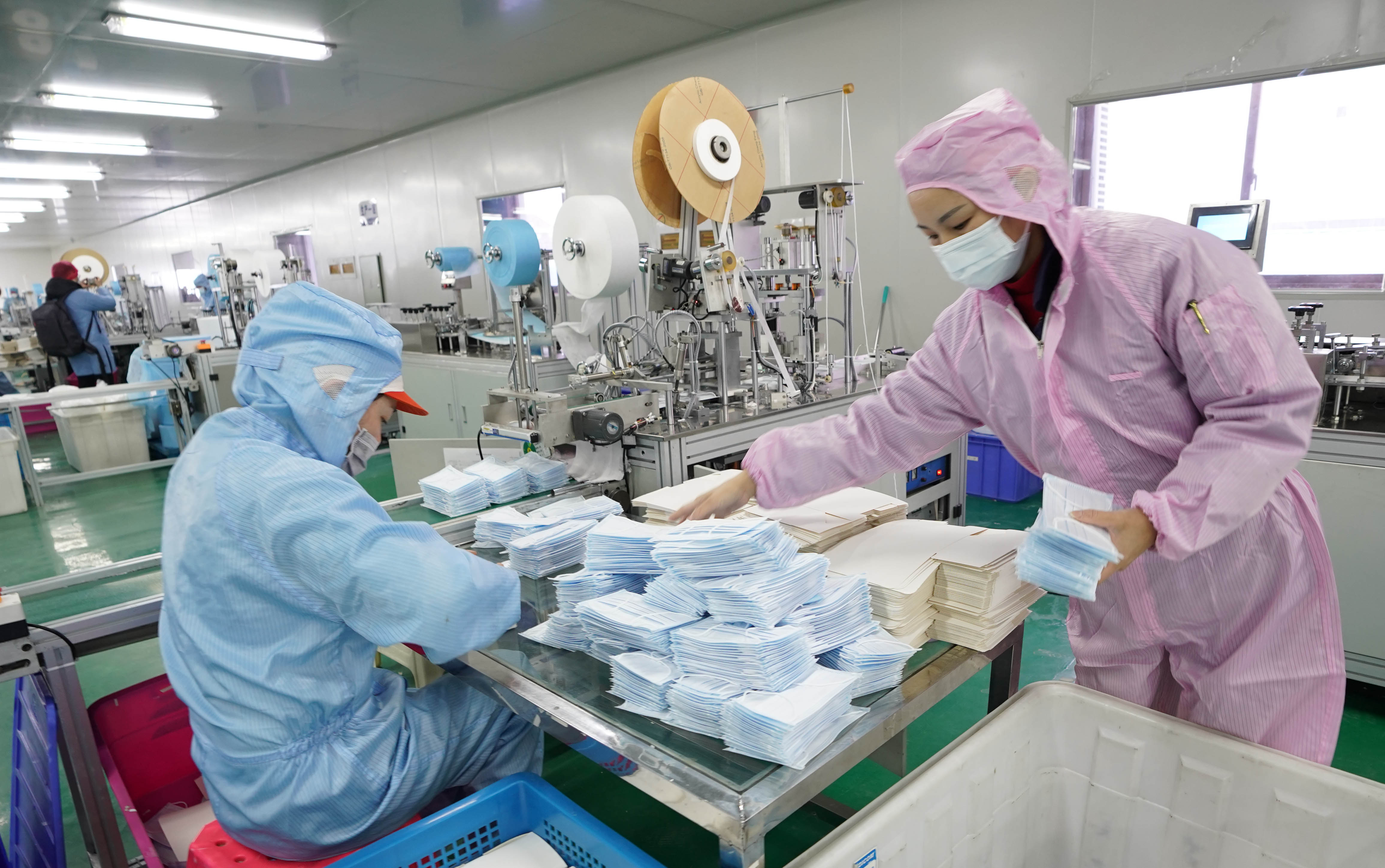 Workers make facial masks at the workshop of a company in Wuhan, central China