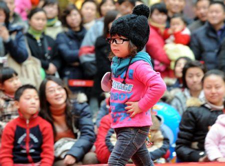 A little girl shows her dress during a fashion show for children in Nanjing, east China's Jiangsu Province, on Dec. 19, 2009. (Xinhua/Sun Can)