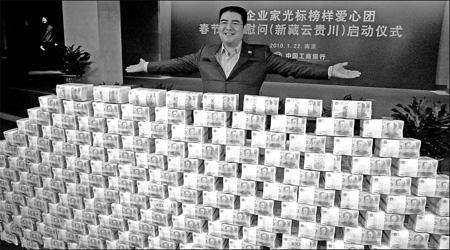Chinese entrepreneur Chen Guangbiao stands behind a wall of banknotes to announce his new charity trip at the Industrial and Commercial Bank's Jiangsu provincial branch last Friday. [China Daily/Wang Chengbing] 