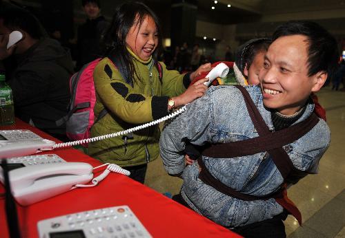 Lu Laofa (R), a 40-year-old migrant worker from southwest China's Guizhou Province, and his children make a free phone call with their relatives at the railway station of Hangzhou, capital of east China's Zhejiang Province, Jan. 31, 2010.(Xinhua/Wang Dingchang)
