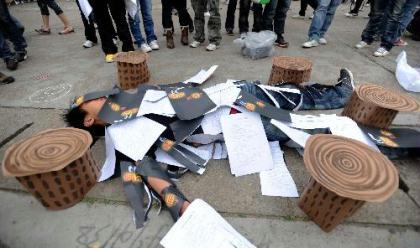 A college student lies in a feign scene of tree stumps and wasted papers during the launching ceremony of 2010 Earth Hour Changsha in Changsha, capital of central China's Hunan Province, March 21, 2010. Volunteers encouraged people here on Sunday to take part in Earth Hour 2010, which will be held on March 27 by switching off unnecessary lights for an hour from 8:30 p.m.to boost the global awareness of climate change. (Xinhua/Li Ga)
