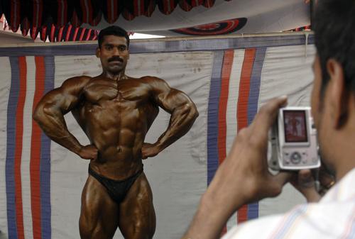 A man takes pictures of a competitor during the "37th Services Best Physique Championship 2010" bodybuilding contest in the southern Indian city of Hyderabad March 24, 2010. Forty eight body builders from the Indian Army, Navy and Air Force on Wednesday participated in a contest organised by the Army Ordnance Corps (AOC), an organiser said.(Xinhua/Reuters Photo)