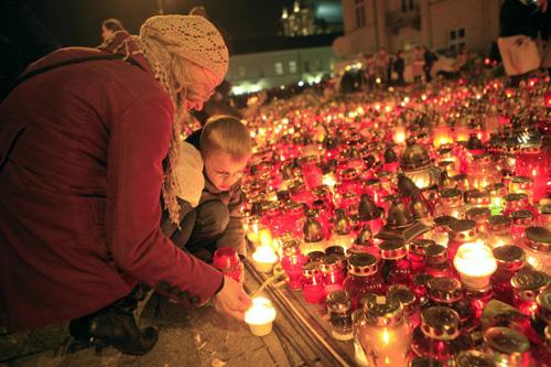 A woman and a boy light candles near the Presidential Palace in Warsaw April 11, 2010. [Agencies] 