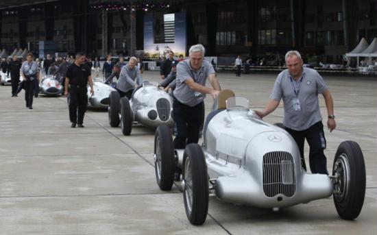 Mechanics push old timer racing cars at a Mercedes Benz vintage car show