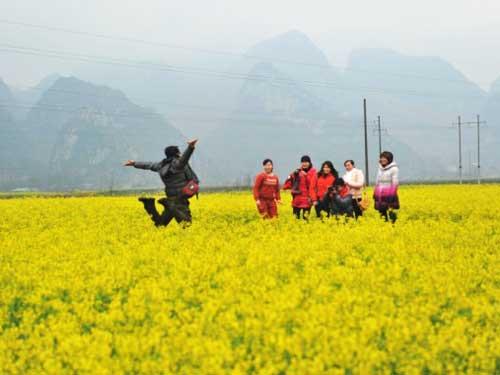 游人在忻城县古蓬镇东河村油菜花丛中拍照