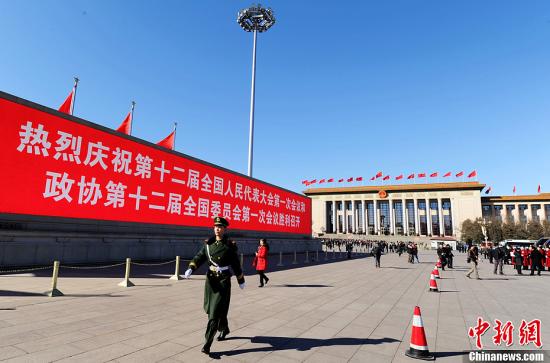 3月4日，北京晴空万里，武警从北京天安门广场大型显示屏前走过。3月5日上午，十二届全国人大一次会议将隆重开幕。中新社发 刘忠俊 摄