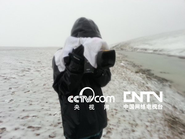 摄像陈鑑开用随身携带的毛巾搭在摄像机上遮挡风雪，但他的衣服已经完全湿透