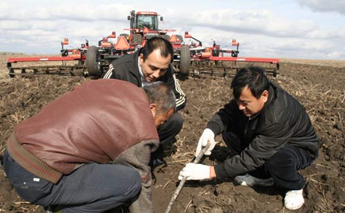 宋金贵在田间测量农机作业效果（右一）