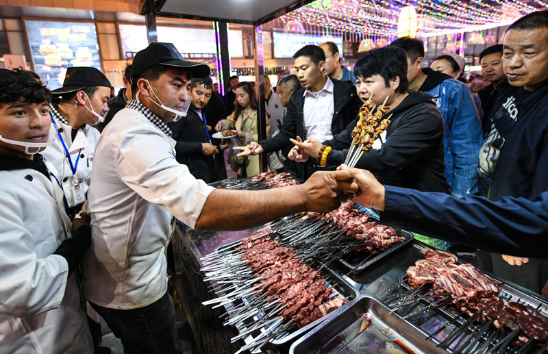 　　在乌鲁木齐五一星光夜市，人们排队购买烤羊肉串等美食（5月6日摄）。新华社记者 王菲 摄