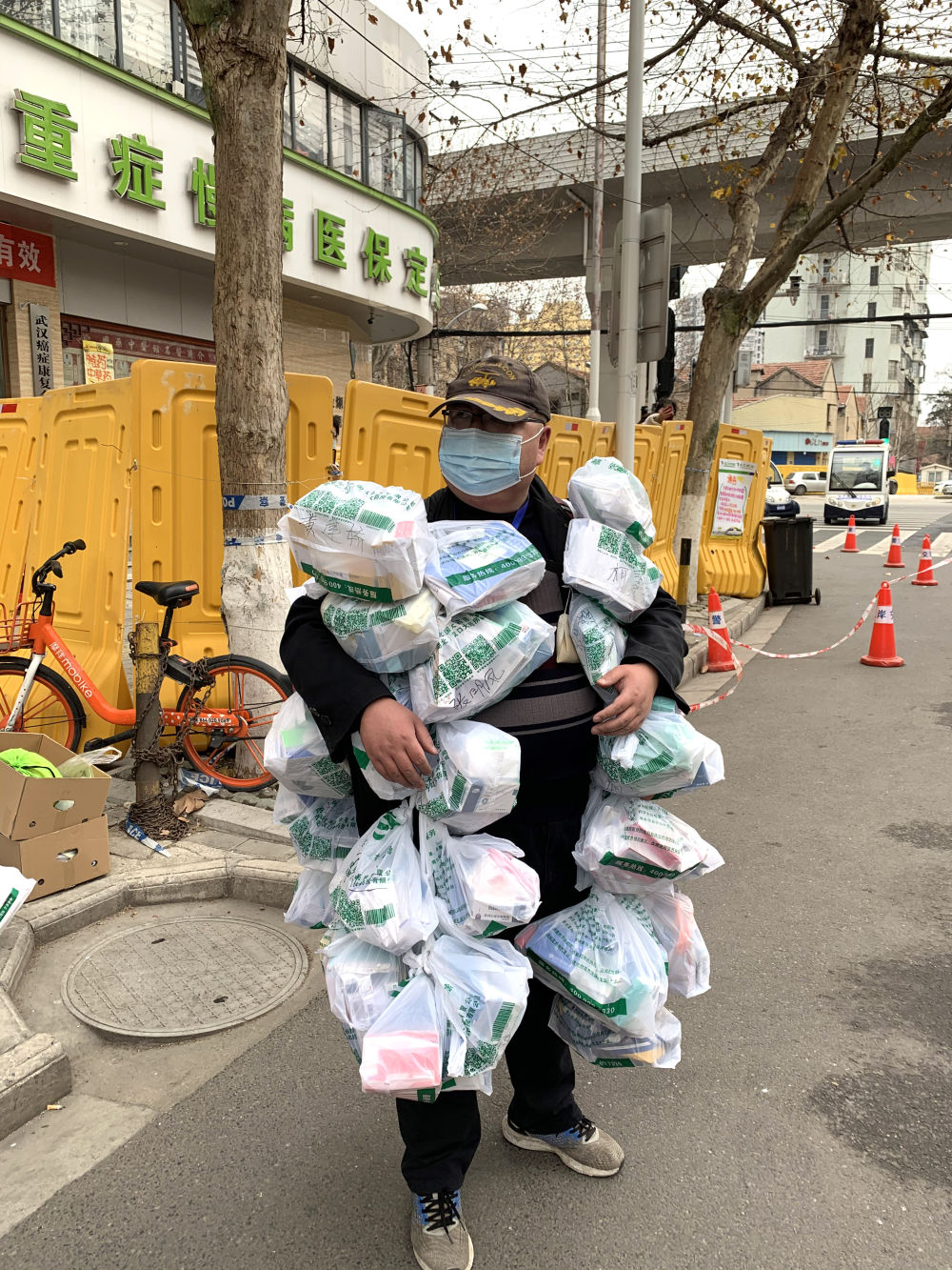 在武汉市江岸区黄石路汉口大药房，惠民苑社区网格员丰枫把为居民购买的药挂在身上（2月24日摄）。新华社发（武汉后湖街道供图）