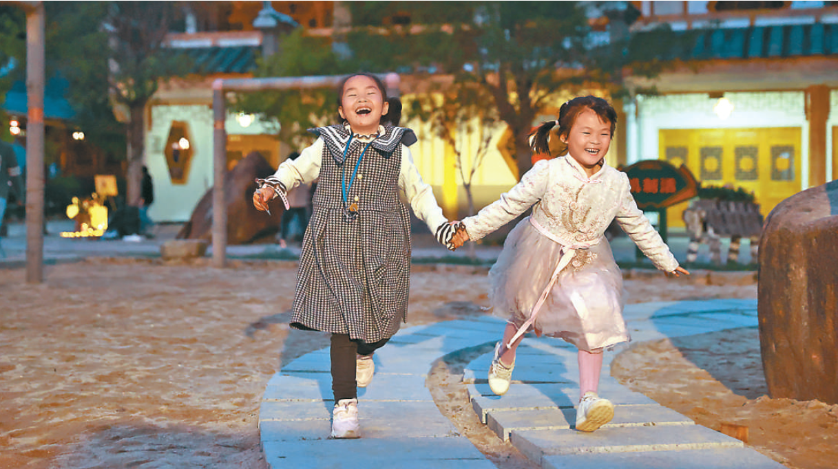 孩童在三明市泰宁县上青乡崇际村口的广场上玩耍。崇际村大力推进道路绿化、河流治理，使村庄面貌焕然一新。本报记者 张武军摄