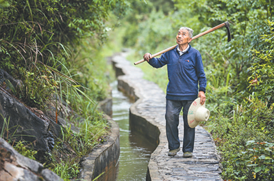 黄大发扛上锄头到大发渠疏通水渠（资料图片）。