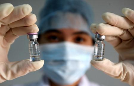 A medical staff with local center for disease control and prevention holds high two pyxises of vaccination against A/H1N1 flu virus, at Dongguan City, south China's Guangdong Province, Oct. 28, 2009.(Xinhua/Chen Fan)