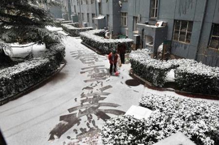Two women clean up snow in the Lugu residential area in Beijing, capital of China, March 14, 2010. A sleet hit Beijing Sunday morning. (Xinhua/He Junchang)