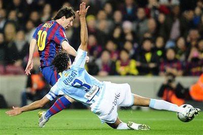 FC Barcelona's Lionel Messi of Argentina, left, duels for the ball against Malaga's Weligton from Brazil during a Spanish La Liga soccer match at the Camp Nou stadium in Barcelona, Spain, Saturday, Feb. 27, 2010. (AP Photo/Manu Fernandez)