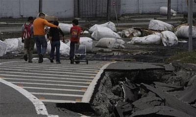 People walk aside a destroyed road in Talcahuano, Chile, Sunday, Feb. 28, 2010, following a devastating earthquake that struck Chile early Saturday Feb. 27. (AP Photo/ Aliosha Marquez)