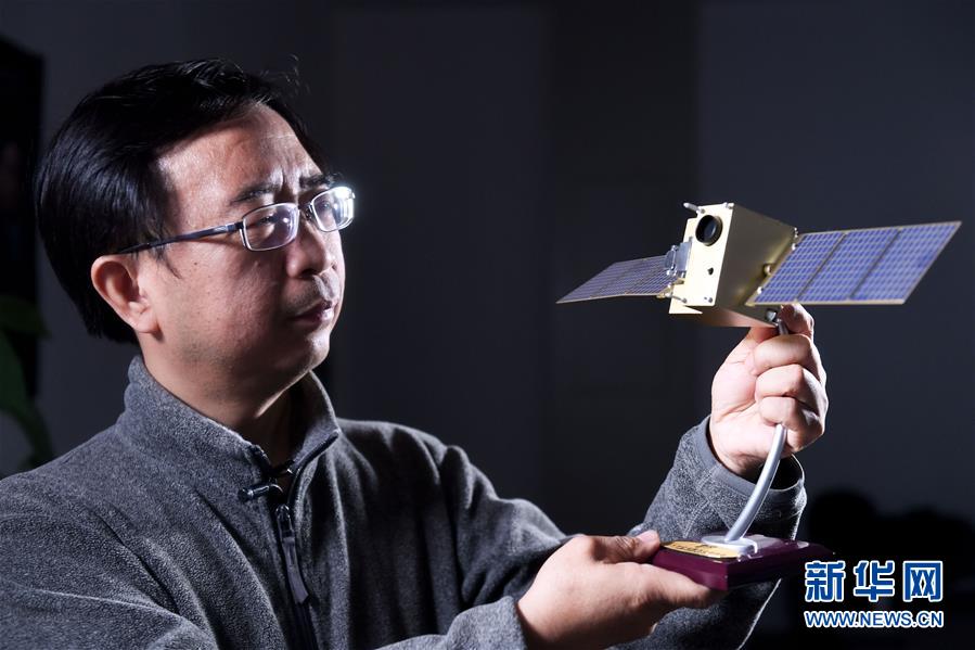 潘建伟在中国科学技术大学的办公室内与“墨子号”量子卫星模型合影（12月13日摄）。