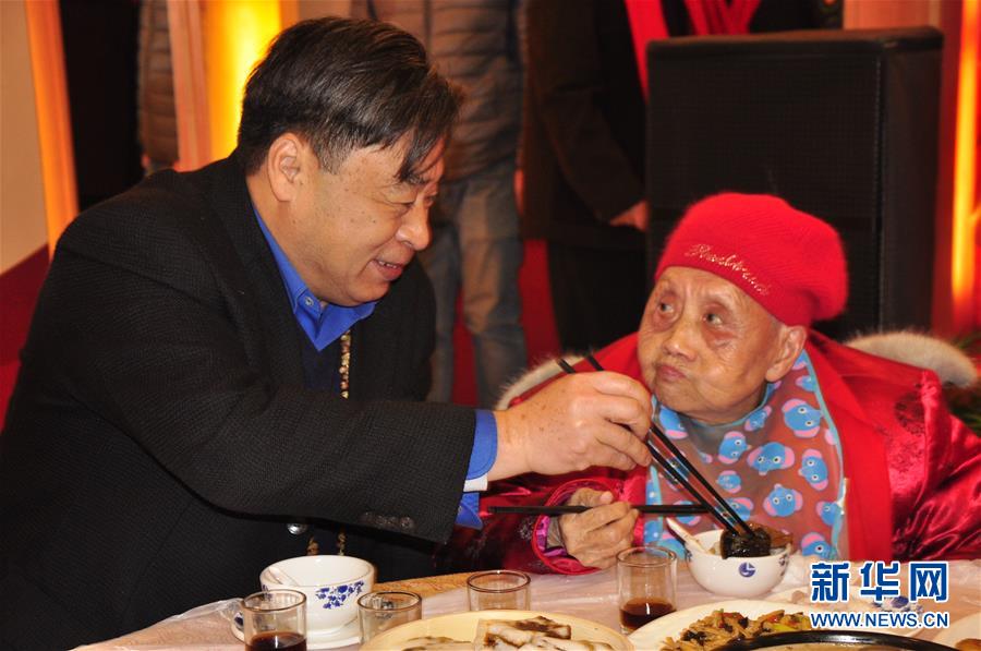 2017年1月21日，茅永红（左）与全国文明家庭代表李声英共享万家宴。新华社发（童汉莲 摄）