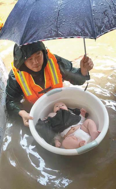图为2020年6月27日，在宜昌市伍家岗区，消防员用水盆将3个月大的婴儿安全转移。 人民视觉  王方/摄