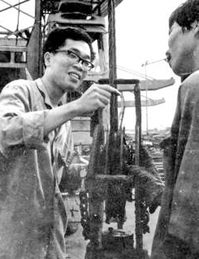 包起帆（左）在上海港码头和工友一道研究装卸货物工作中存在的问题（资料照片）。新华社发