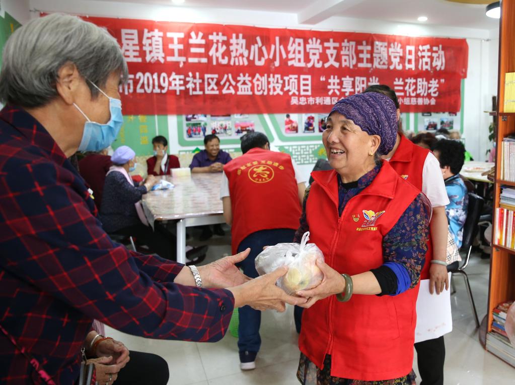 王兰花（右）向来到兰花志愿服务站参加活动的老人发放“爱心水果”。（2020年6月23日摄）新华社记者贾浩成摄