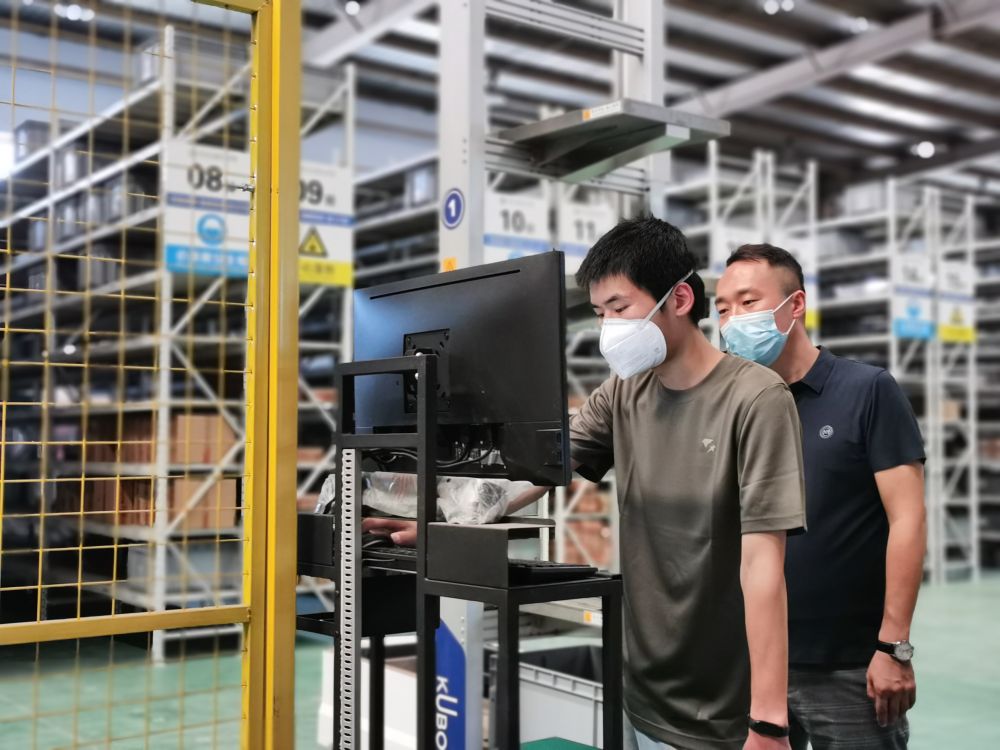 在天津交通职业学院产教融合数智化供应链生产性实训中心，人员正在操纵料箱式机器人工作。