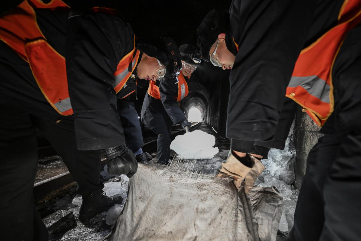 为防止击落的冰块二次结冰，队员们要将几十斤重的冰块搬运出隧道。（图片由太原局太原工务段赵哲昌提供）