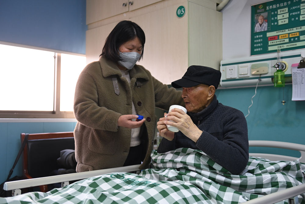 　　罗锦文儿媳柳燕（左）在浙江省平湖市一家老年康复护理院照顾罗锦文老人（3月2日摄）。