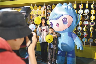 5月7日，在浙江省杭州市湖滨步行街“3D笑脸墙”前，摄影师为游客与杭州亚运会吉祥物之一“宸宸”拍摄合影。