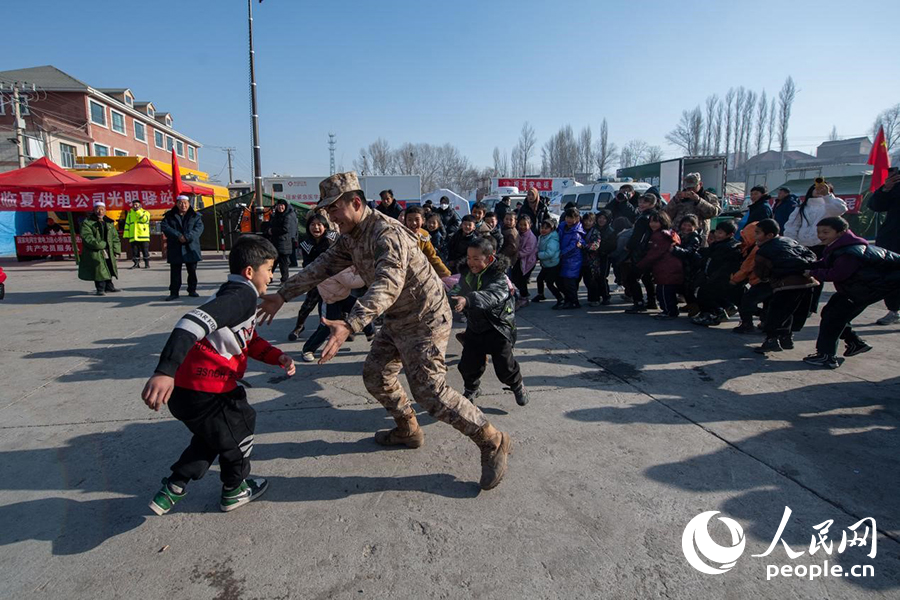 12月22日，在积石山县大河家镇大河村安置点，陆军76集团军某旅官兵通过游戏方式，对小朋友进行灾后心理疏导。人民网记者 翁奇羽摄