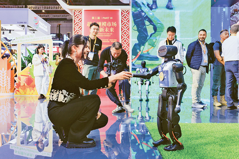 2025年11月5日至10日，第八届中国国际进口博览会在上海举办。图为11月5日，在第八届进博会国家展中国馆，一名外国参展商和机器人握手。据了解，本届进博会上，中国馆全面展示我国&ldquo;十四五&rdquo;期间全面深化改革、推进高水平开放的最新成就，众多科技成果引人瞩目。