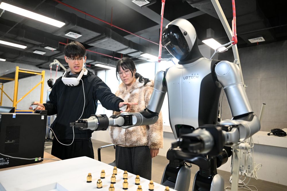 2026年2月11日，在广西柳州机器人产业园里，&ldquo;00后&rdquo;机器人训练师吴东波（左）和同事讨论工业人形机器人作业动作练习要领。