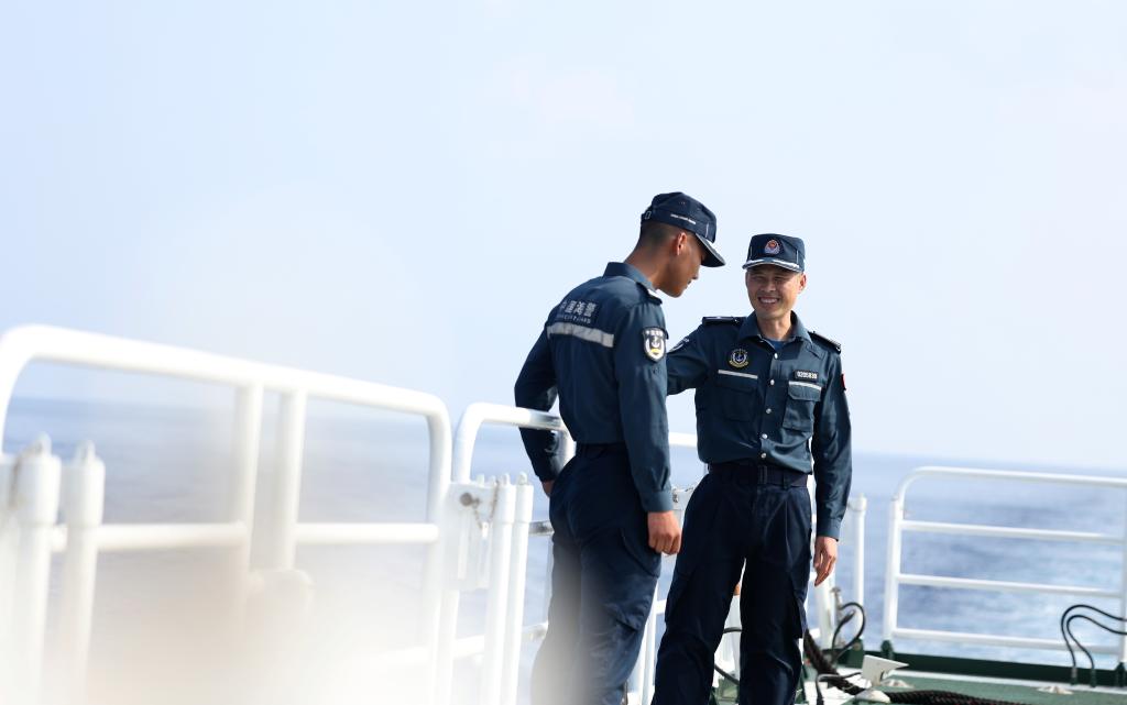 5月20日，海警执法员张继祥（右）和王鑫在川山舰甲板上交流。新华社记者 陈斌 摄